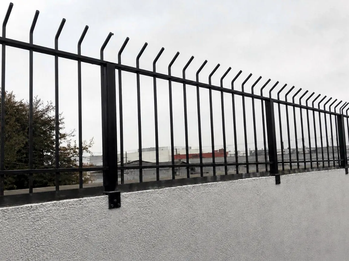 Gradil preto de barras com ponta em lança, instalado sobre muro branco com bases chumbadas