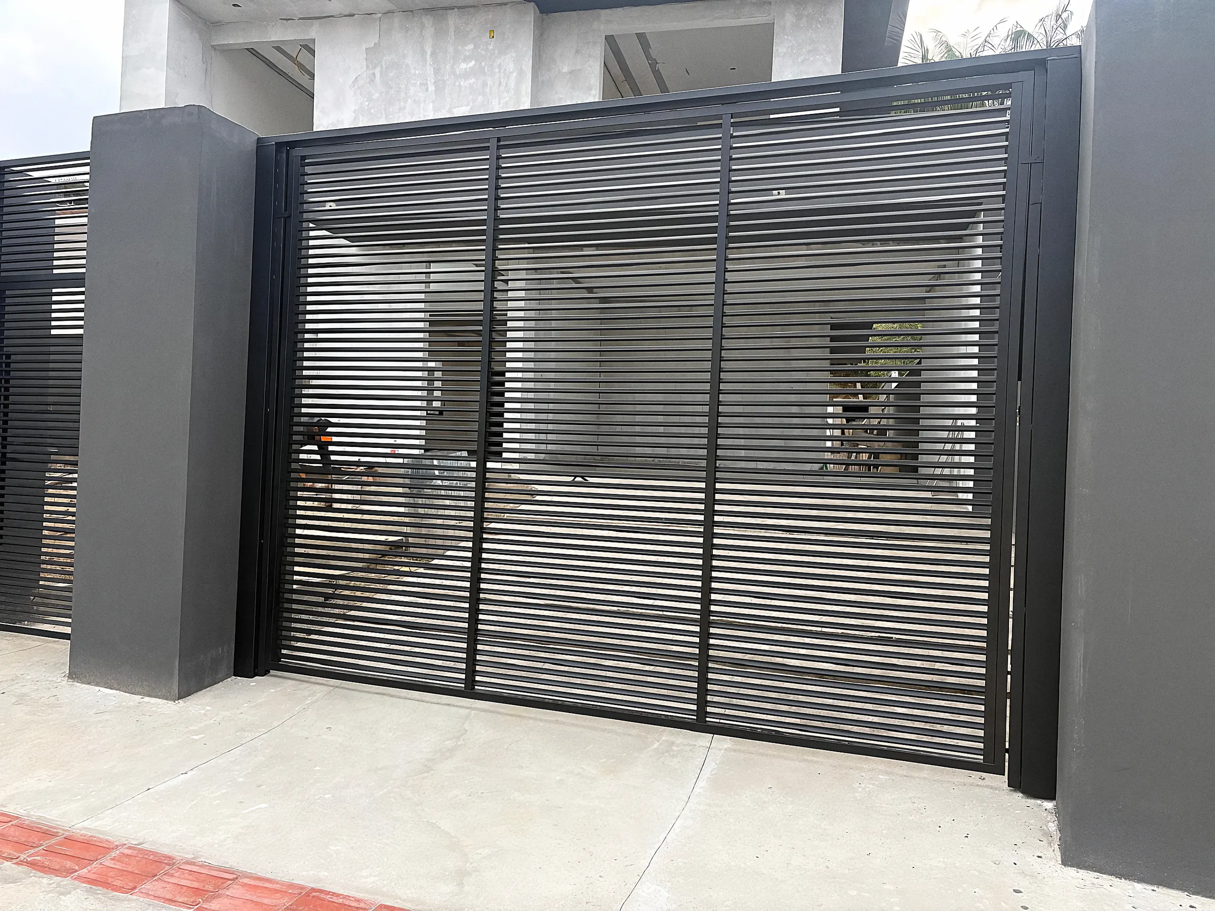 Portão ripado preto integrado a muro cinza